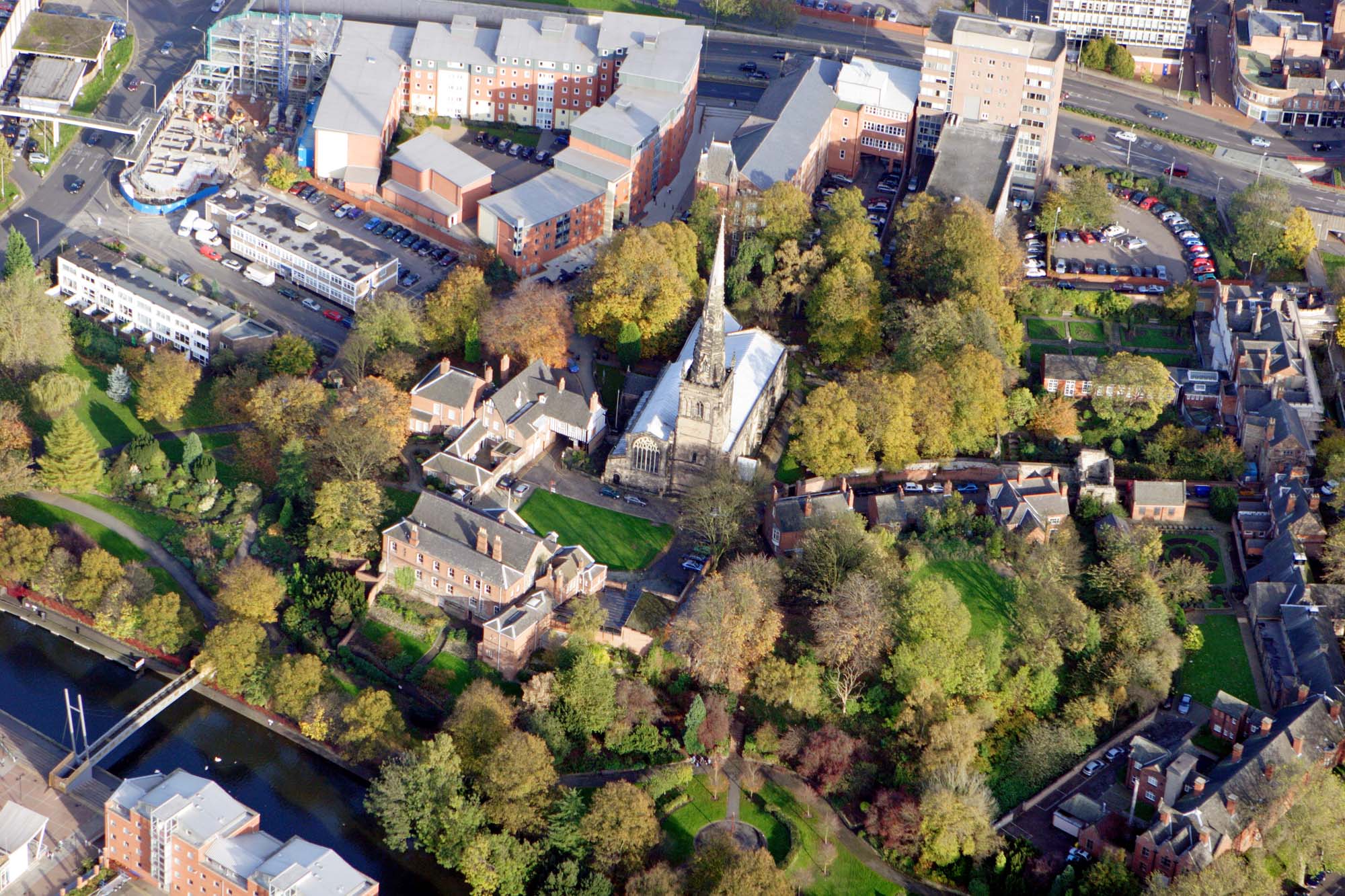 An aerial view of Leicester Castle from the west. The church of Mary de Castro is in the centre, with the Great Hall and Castle Gateway to the left and the castle motte surrounded by trees - University of Leicester Archaeological Services