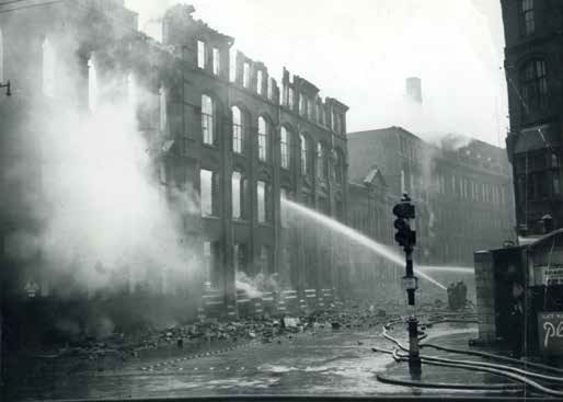 Firemen in Rutland Street damp down the ruins of the Freeman, Hardy and Willis building the morning after the bombing - Austin J. Ruddy