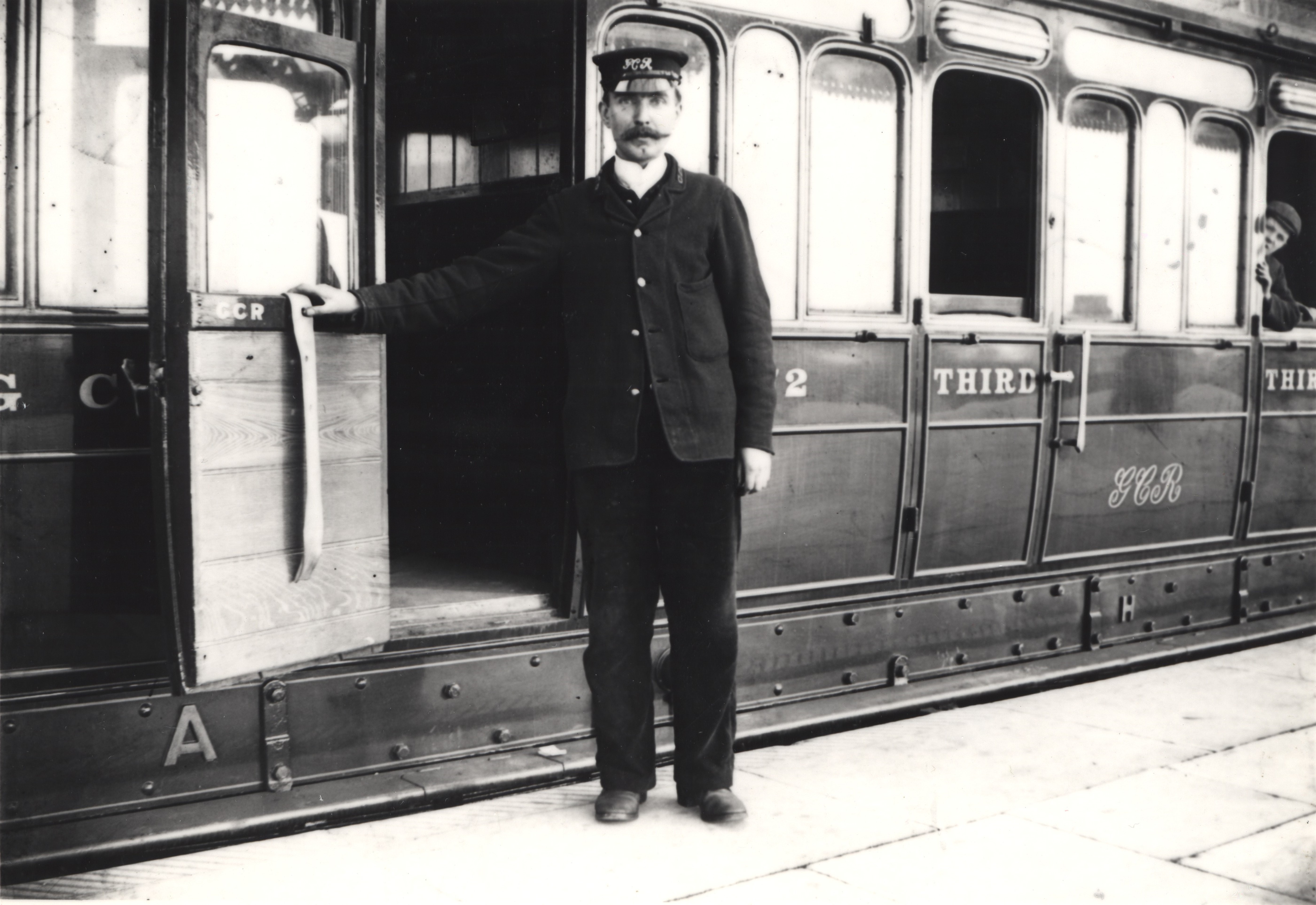 A porter poses for the camera beside a third class carriage at the Station, 1900 - Leicester & Leicestershire Record Office